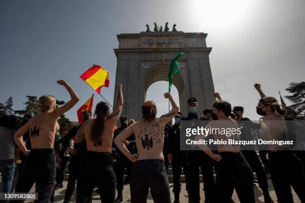 Activists wearing body paint raise their fists during a gathering of right-wing supporters at Arco de la Victoria commemorating the 82nd anniversary...