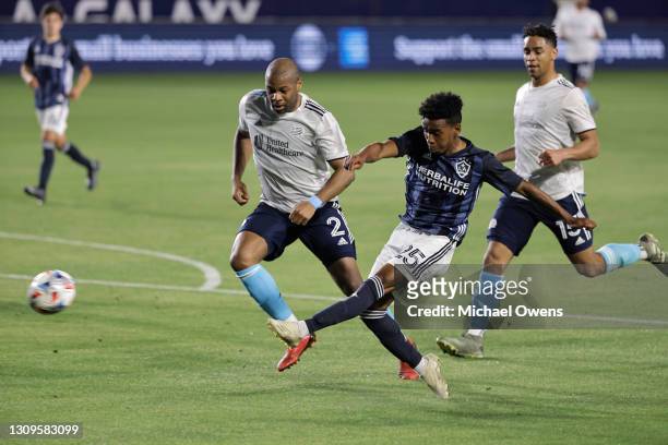 Cameron Dunbar of Los Angeles Galaxy takes a shot on goal as Andrew Farrell of New England Revolution defends during the first half at Dignity Health...
