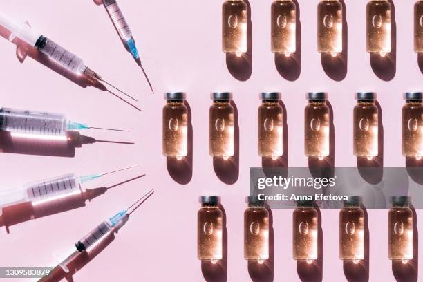 pattern made with set of clean syringes placed near vial of liquid drug near copy space on pink background with shadows and light reflections. flat lay style - botox injection stock pictures, royalty-free photos & images