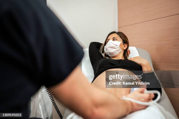 pregnant woman watching her baby on the ultrasound - doctor abdomen stock pictures, royalty-free photos & images