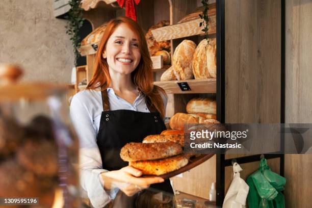 junge rothaarige frau in bäckerei-shop wahl gebäck - baker stock-fotos und bilder