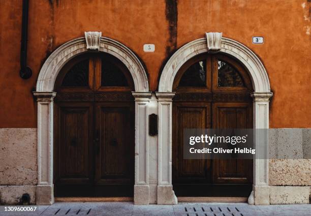 two almost identical antique doors of an old house in italy - arches stock-fotos und bilder