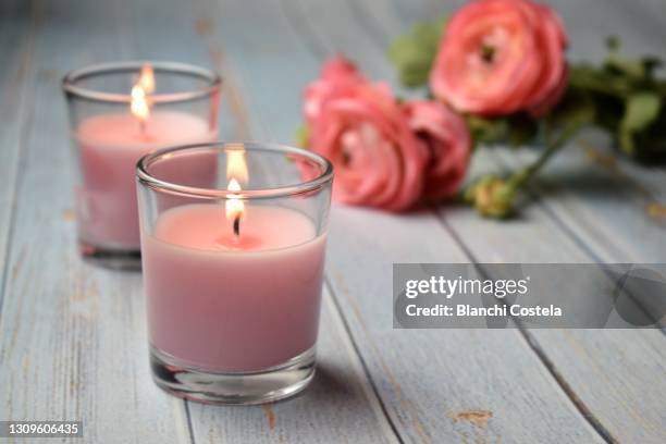 scented pink candles with flowers in the background - aromaterapia foto e immagini stock