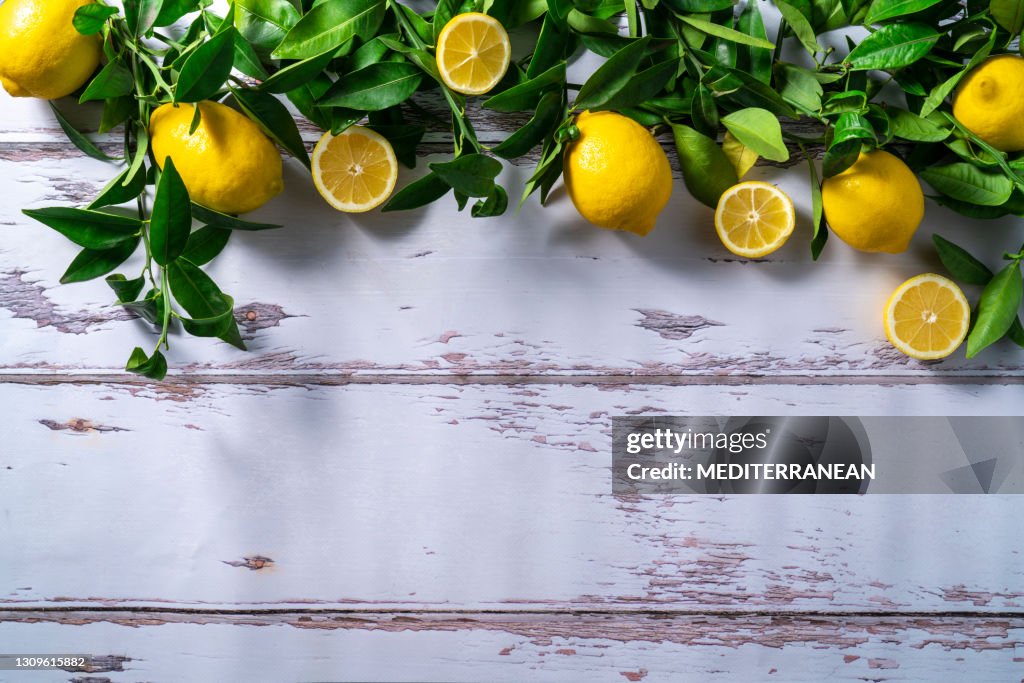 Lemon fruits in branches and leaves of lemon tree on rustic wood
