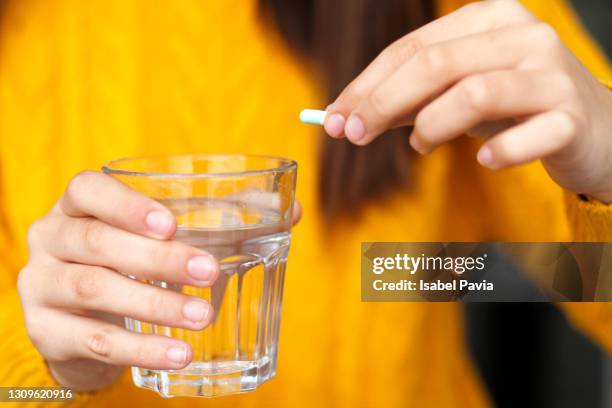 mid-section of woman holding pill and water glass - antibiotic resistant fotografías e imágenes de stock