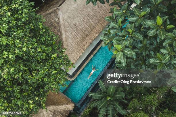 woman enjoying alone in luxury swimming pool, drone view from above - private wealth stock pictures, royalty-free photos & images