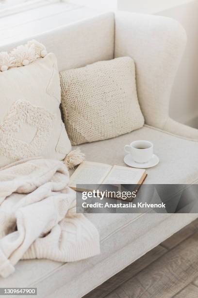 empty couch with beautiful pillow, tea cup and book. - knitted house stock pictures, royalty-free photos & images