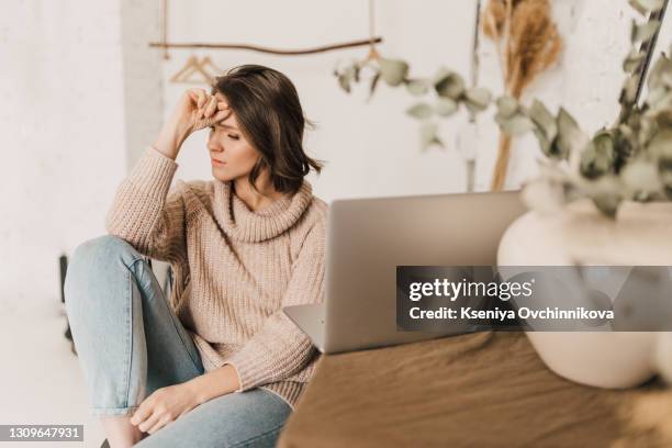 a tired woman in front of a laptop - hand on head stockfoto's en -beelden