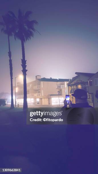 a man looks at his mobile phone during the night during a fog storm - hot latin nights stock pictures, royalty-free photos & images