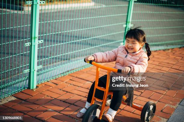 happy little girl riding tricycle in playground - like a child in a sweet shop stock pictures, royalty-free photos & images