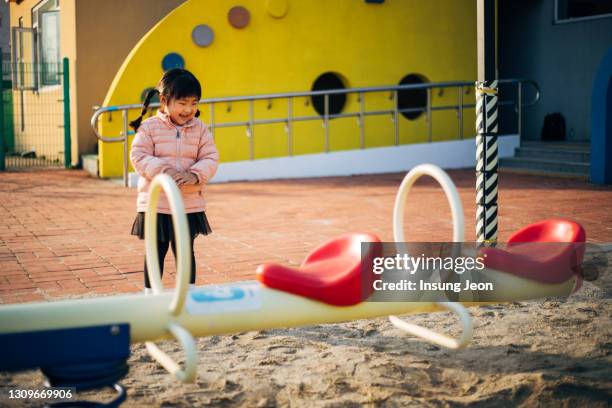 happy little girl playing on seesaw in playground - like a child in a sweet shop stock pictures, royalty-free photos & images