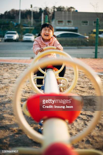 happy little girl playing on seesaw in playground - like a child in a sweet shop stock pictures, royalty-free photos & images