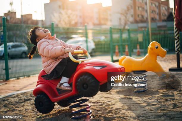 happy little girl sitting on a rocker in playground - like a child in a sweet shop stock pictures, royalty-free photos & images