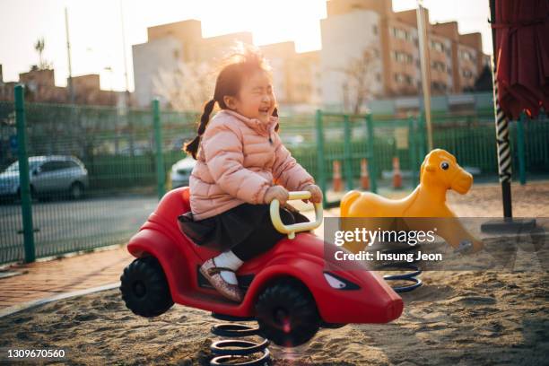 happy little girl sitting on a rocker in playground - like a child in a sweet shop stock pictures, royalty-free photos & images