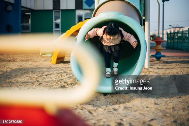happy little girl playing on a slide in playground - like a child in a sweet shop stock pictures, royalty-free photos & images