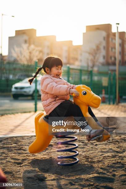 happy little girl riding horse in playground - like a child in a sweet shop stock pictures, royalty-free photos & images