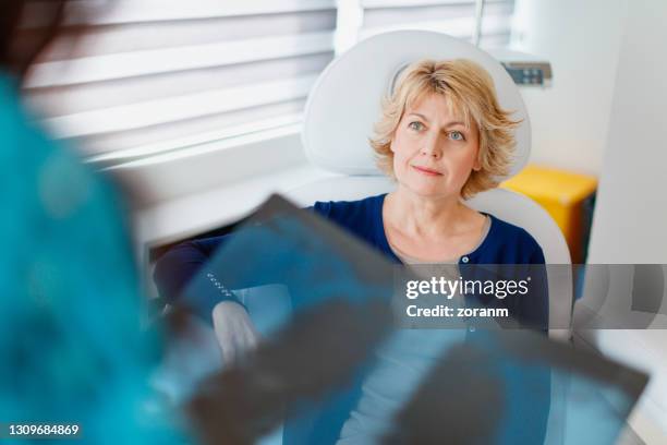 female patient looking with hope in her eyes at doctor with x-ray result - asthma lungs stock pictures, royalty-free photos & images