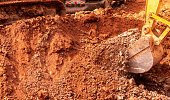 Backhoe digging soil at construction site. Bucket of backhoe digging soil. Crawler excavator digging on dirt. Excavating machine. Earth moving machine. Excavation vehicle. Backhoe working on suny day.