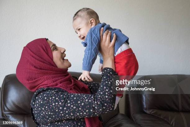ehrliches porträt der britischen asiatischen mutter mit glücklichen baby junge - pakistanischer abstammung stock-fotos und bilder