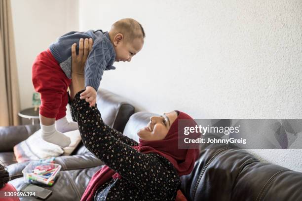 mid adult british asian mother lifting her laughing baby boy - indian baby boy stock pictures, royalty-free photos & images