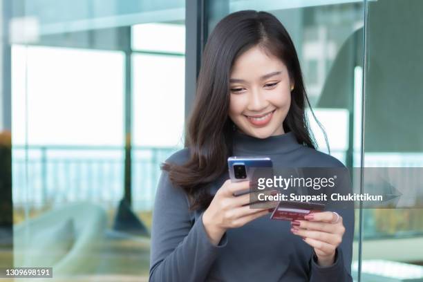 asian woman holding hand smartphone shopping - phone credit card stock-fotos und bilder