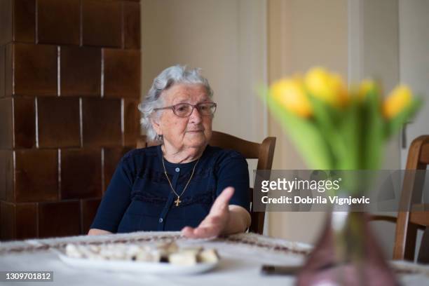 older woman sitting at a table and talking - covid-19 guidance stock pictures, royalty-free photos & images