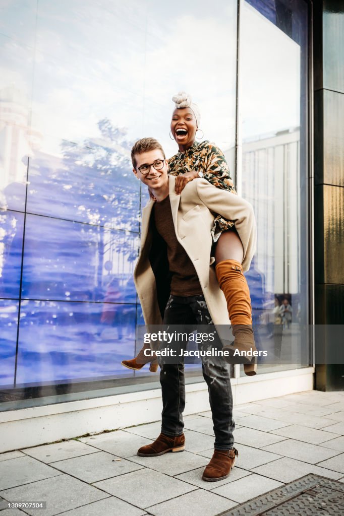 Portrait of a happy couple in the city - the man gives her a piggyback ride