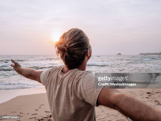 uomo su scooter braccia fuori, spiaggia al tramonto - mare moto foto e immagini stock