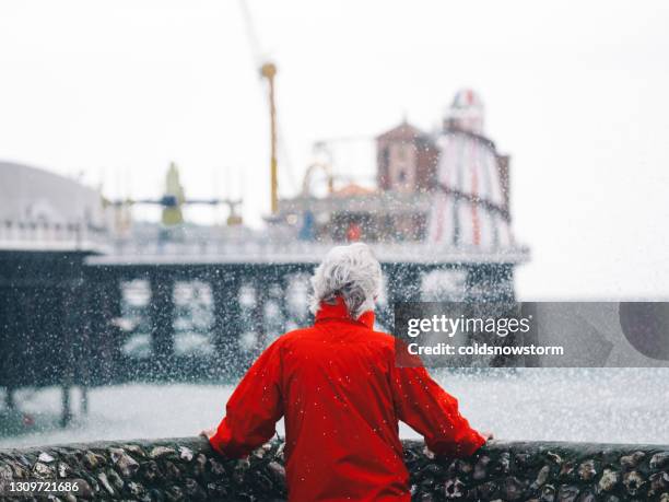 senior man looking out at stormy sea and powerful waves - coastal deprivation stock pictures, royalty-free photos & images