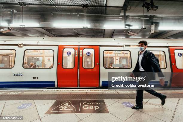 blurred motion of man walking on london underground subway platform - london underground train stock pictures, royalty-free photos & images