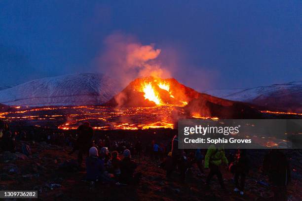 People's figures are illuminated by the glow of the lava field on March 28, 2021 on the Reykjanes Peninsula, Iceland. The Mount Fagradalsfjall...