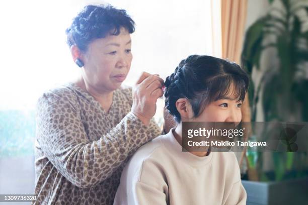 grandmother tying granddaughter's hair at home - japan 12 years girl stock pictures, royalty-free photos & images