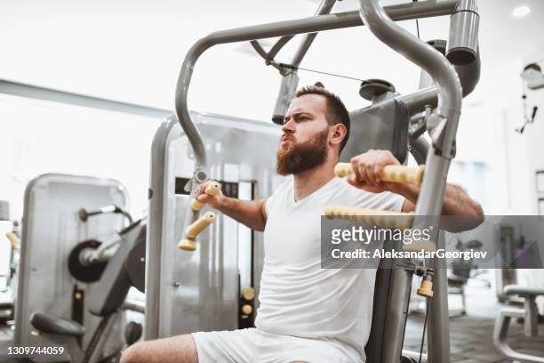 fokussierte männliche athlet arbeiten hart in gym - brustmuskulatur stock-fotos und bilder