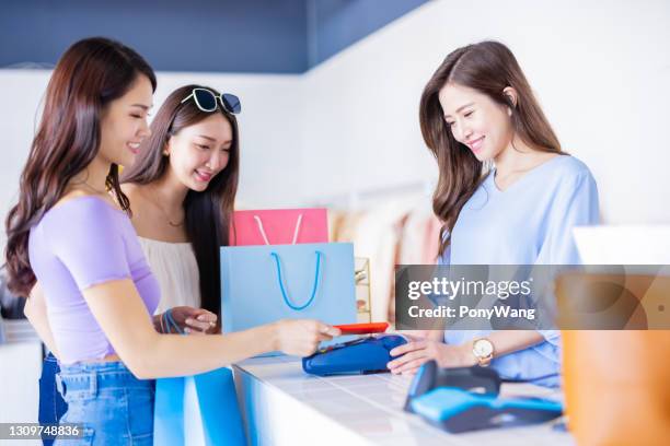 women pay by smartphone - clothes shop counter stock pictures, royalty-free photos & images