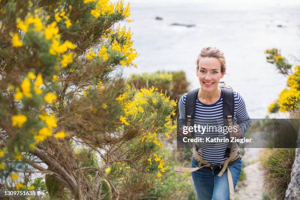 woman hiking on coastal footpath, looking at camera - female active stockfoto's en -beelden