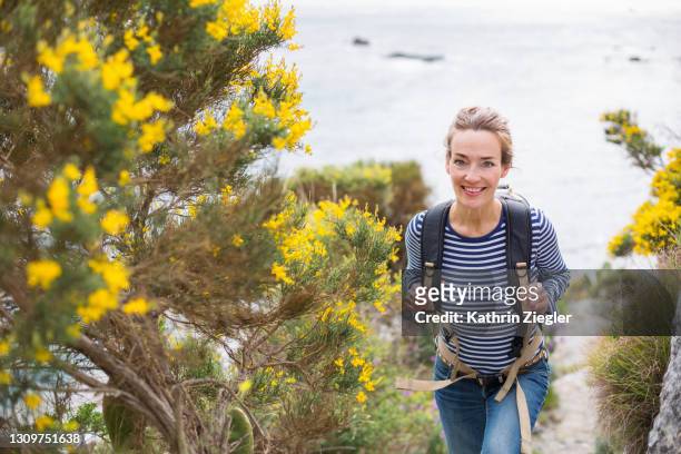 woman hiking on coastal footpath, looking at camera - backpacker woman bildbanksfoton och bilder