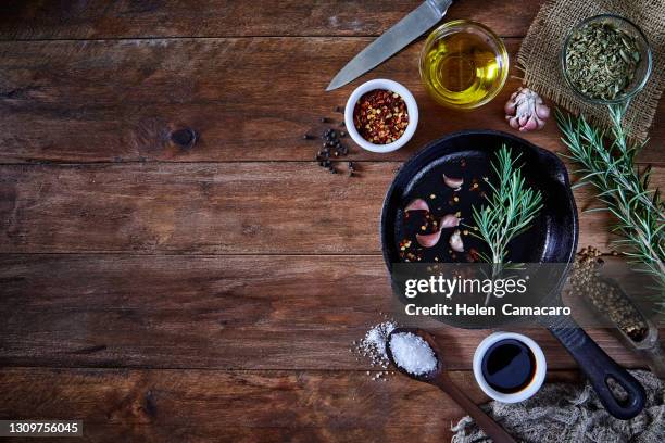 top view of a rustic wooden table with fresh spices ready for cooking. - frying pan from above stock pictures, royalty-free photos & images