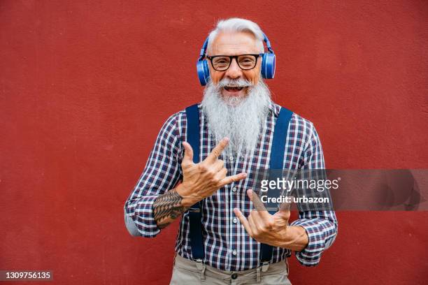 schöne senior bärtige mann mit headset lächelnd - alter mann jung geblieben stock-fotos und bilder