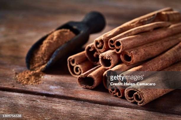 stick cinnamon and cinnamon powder on rustic wooden table with copy space - canelo fotografías e imágenes de stock