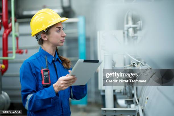 smart female maintenance engineer using digital tablet and standing in front of pump valve control panel while examining about steam boiler pressure and temperature and record of measuring in boiler control room of factory. - leading indicators stock pictures, royalty-free photos & images