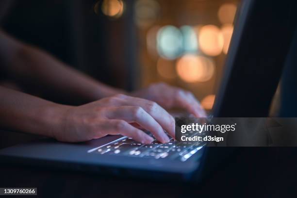 close up of woman's hand typing on computer keyboard in the dark, working late on laptop at home - cyber security stock-fotos und bilder