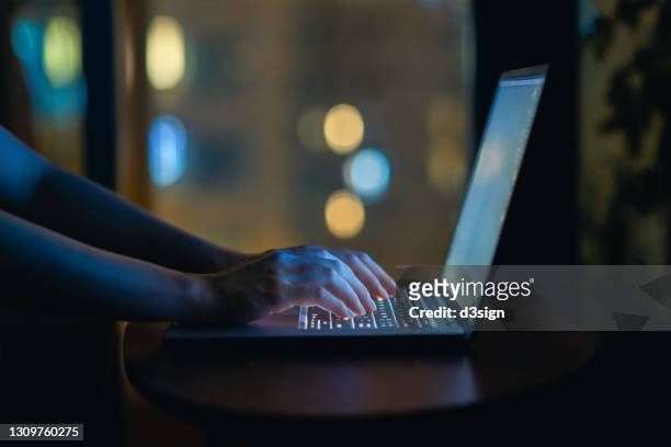 cropped shot of woman's hand typing on computer keyboard in the dark, working late on laptop at home - firewall stock pictures, royalty-free photos & images