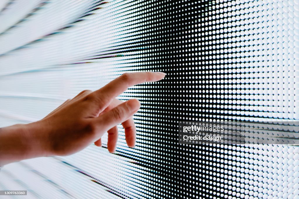 Close up of woman's hand touching illuminated LED display screen, connecting to the future