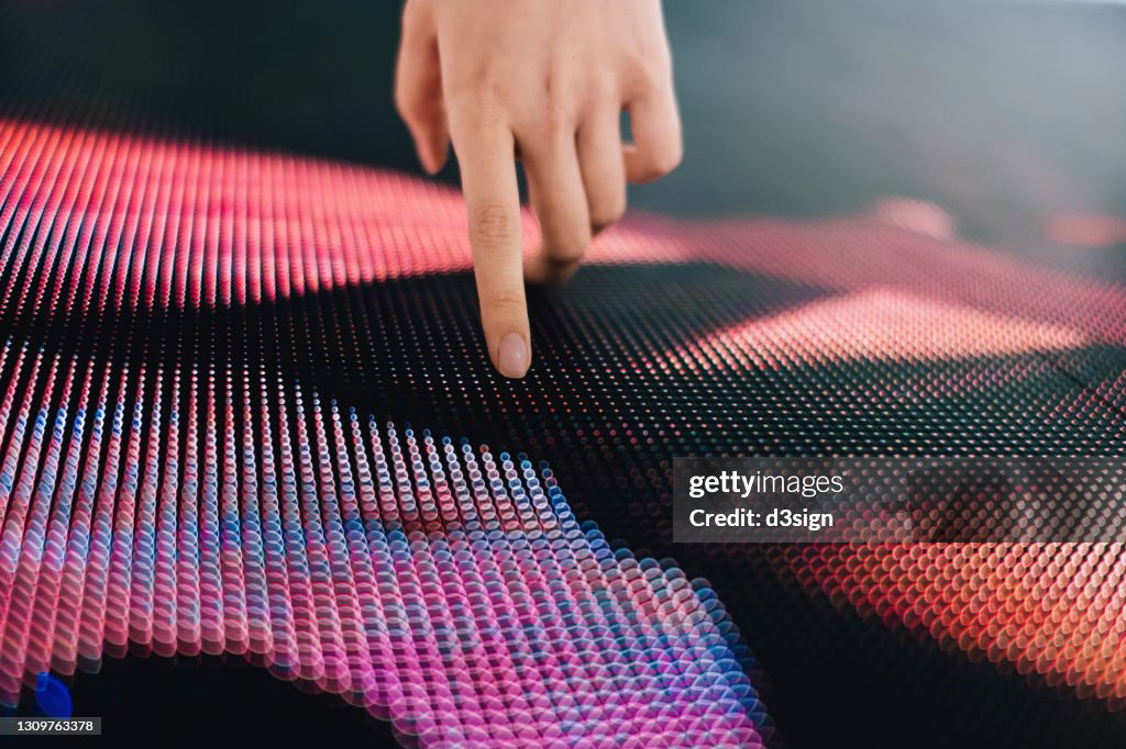 Close up of woman's hand touching illuminated LED display screen, connecting to the future