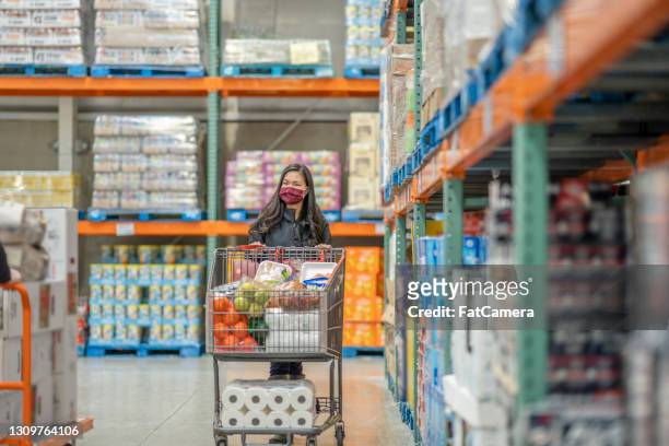 亞洲女人推著裝滿雜貨的購物車 - 大賣場 個照片及圖片檔