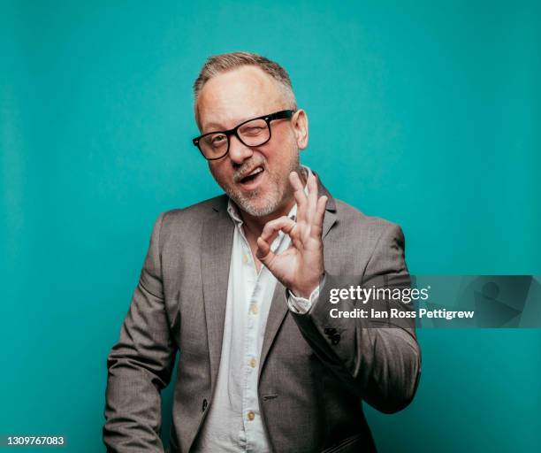 middle-aged businessman making ok sign with hand - winking fotografías e imágenes de stock