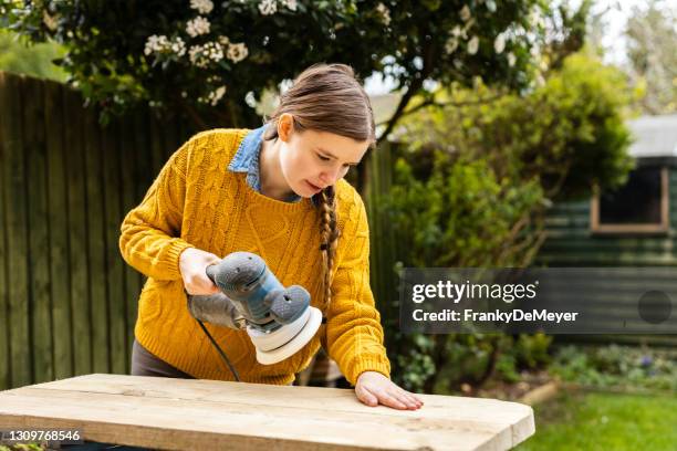 sanding recycled wood. young independent home business owner doing environmental woodworking using recycled materials for furniture. - sand paper stock pictures, royalty-free photos & images