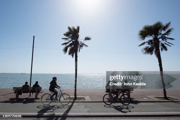 People sit on benches as cyclists pass by on the promenade beside the beach in the warm weather on March 29, 2021 in Southend, England. Today the...