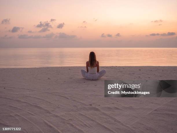 woman exercising yoga at sunrise on the beach - zenlike stock pictures, royalty-free photos & images