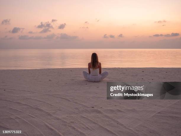 kvinna som utövar yoga vid soluppgången på stranden - meditera bildbanksfoton och bilder